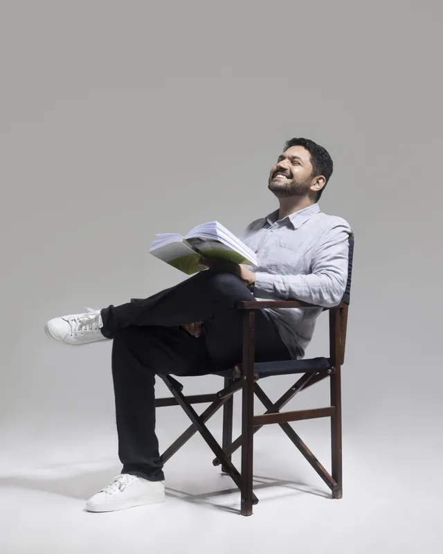 Dr. Fernando Crisanto sentado com um livro aberto, sorrindo e olhando para cima