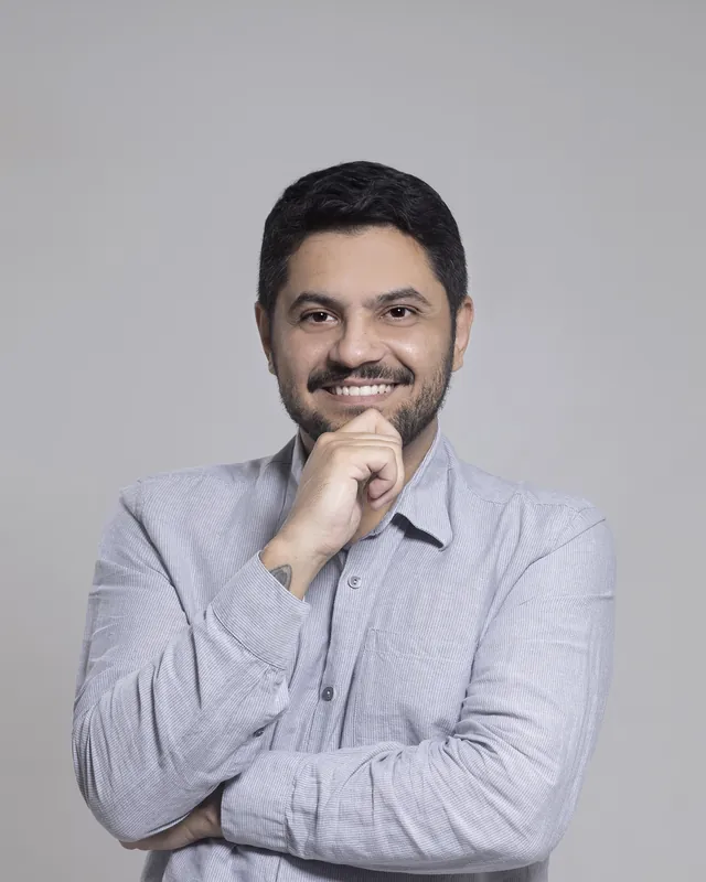 Dr. Fernando Crisanto de camisa cinza clara, com a mão no queixo