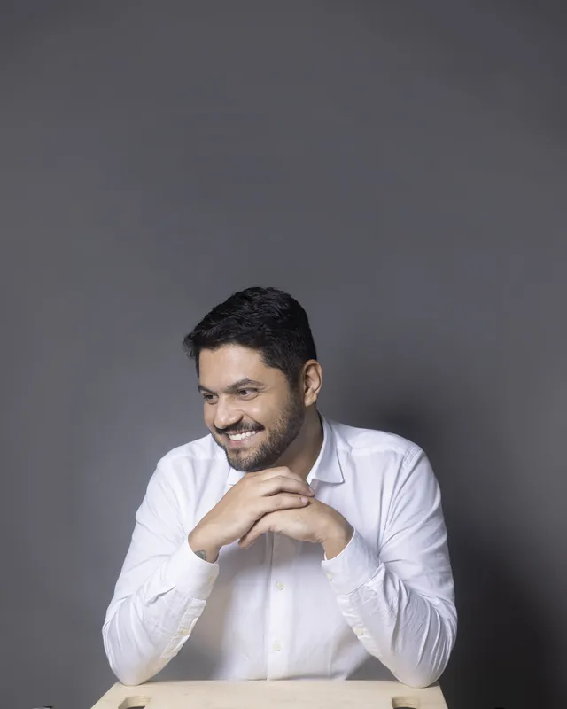 Dr. Fernando Crisanto de camisa branca, mãos entrelaçadas, sorrindo